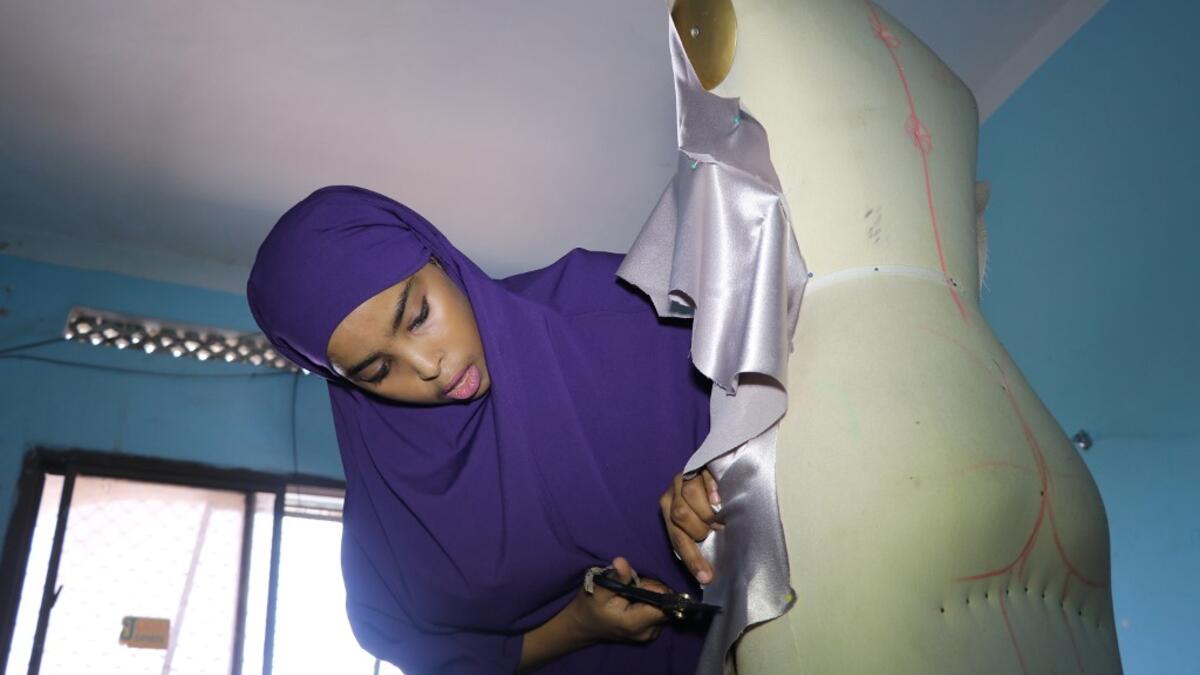 Muna Mohamed Abdullahi, 24 years old, owner of Mkena Designs, cuts some fabrics on a mannequin on November 4, 2018, in Mogadishu. Abdi HAJJI HUSSEIN / AFP