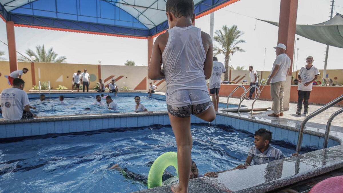 A Palestinian amputee child prepares to jump into the pool during a summer camp origanized by the Palestinian Children's Relief Fund (PCRF) in the town of Khan Yunis in the southern Gaza strip on August 3, 2019. SAID KHATIB / AFP