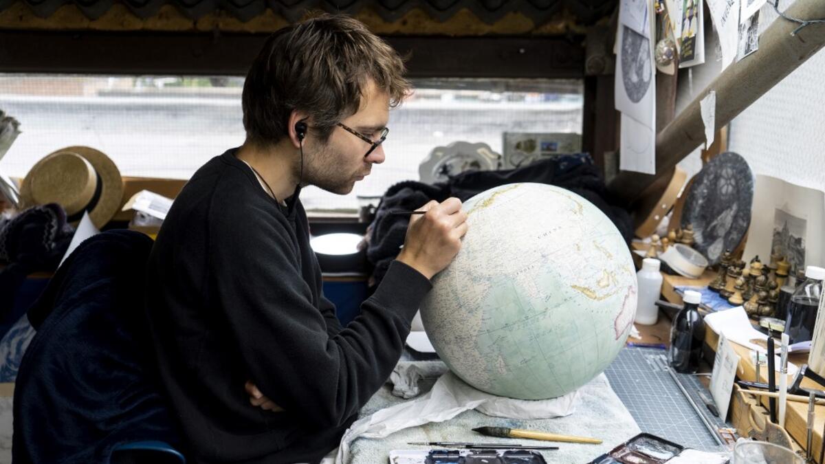 An artist applies paintwork to a globe at the Bellerby and Co Globemakers' workshop and headquarters in Stoke Newington in north London, on July 19, 2019. Niklas HALLE'N / AFP