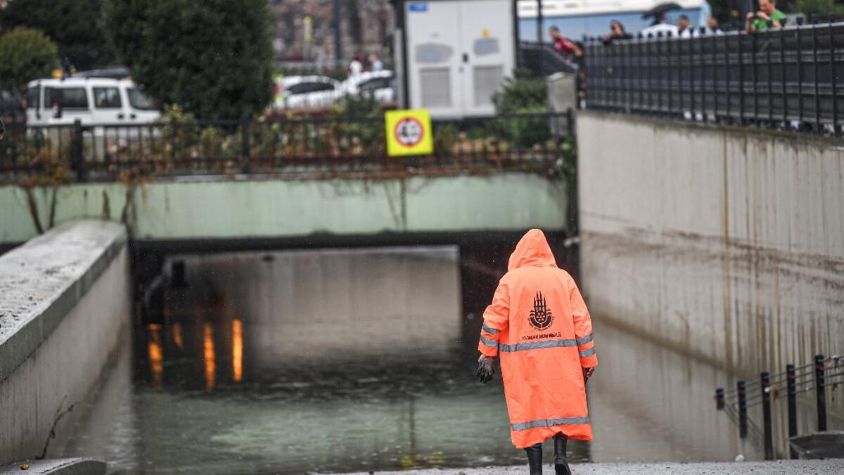 A municipality worker walks near a flooded underpass after a heavy rainfall, in Eminonu district, Istanbul, on August 17, 2019. Turkey's mega city Istanbul was lashed by a heavy rainstorm on August 17, killing a homeless man and leaving parts of the historic Grand Bazaar flooded.  Ozan KOSE / AFP