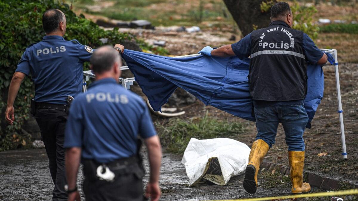 Turkish police officers cover a body on the ground in Eminonu district, Istanbul, after a heavy rainfall, on August 17, 2019. Turkey's mega city Istanbul was lashed by a heavy rainstorm on August 17, killing a homeless man and leaving parts of the historic Grand Bazaar flooded.  Ozan KOSE / AFP