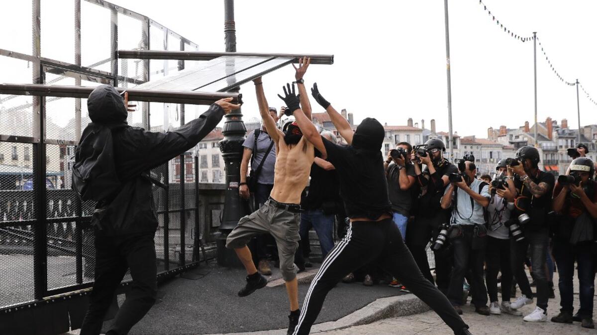 Photojournalist take pictures as three protesters tear down a barricade during demonstration in the city of Bayonne, south-west France on August 24, 2019, on the sidelines of the annual G7 Summit. Thomas SAMSON / AFP
