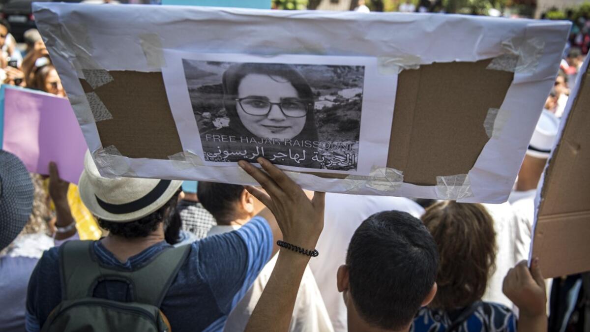 Demonstrators hold up a sign showing the portrait of Hajar Raissouni, a Morrocan journalist of the daily newspaper Akhbar El-Youm, with a caption below in Arabic and English reading "Free Hajar Raissouni" as they gather outside a courthouse holding her trial on charges of abortion in the capital Rabat on September 9, 2019. FADEL SENNA / AFP