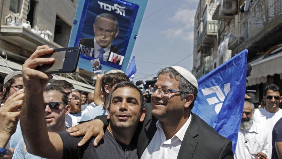 Leader of the far right 'Otzma Yehudit' (Jewish power) party Itamar Ben-Gvir poses for a selfie with a supporter as he campaigns at the Mahane Yehuda Market in Jerusalem on September 13, 2019. MENAHEM KAHANA / AFP