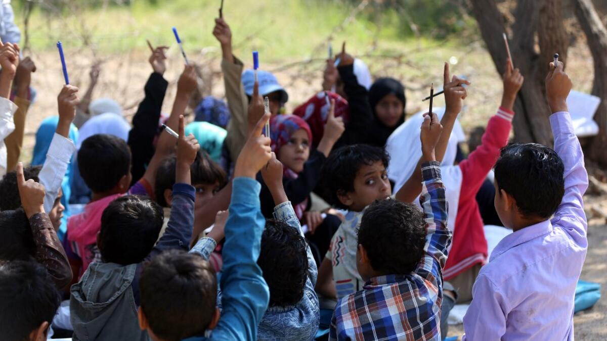 School children attend an open-air class under a tree near their unfinished school  Ahmad AL-BASHA / AFP