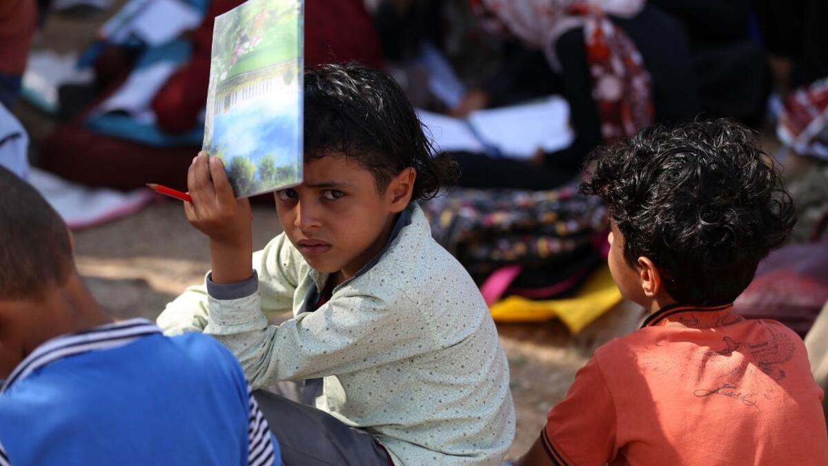 School children attend an open-air class under a tree near their unfinished school  Ahmad AL-BASHA / AFP