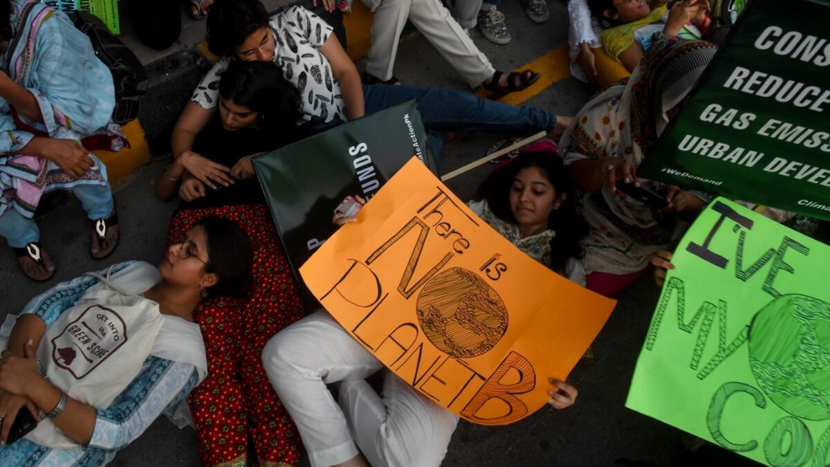 Youths hold placards as lie on the ground during a climate strike to protest against governmental inaction towards climate breakdown and environmental pollution, part of demonstrations being held worldwide in a movement dubbed "Fridays for Future", in Karachi on September 20, 2019. ASIF HASSAN / AFP