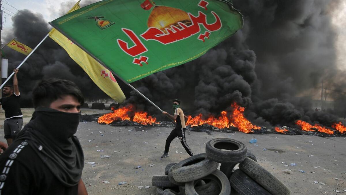 An Iraqi protester waves an Iraqi Hezbollah flag during a demonstration against state corruption, failing public services and unemployment in the Baladiyat district of the capital Baghdad on October 2, 2019. Iraq's president and the United Nations urged security forces to show restraint after two protesters were killed in clashes with police that other top officials blamed on "infiltrators." AHMAD AL-RUBAYE / AFP