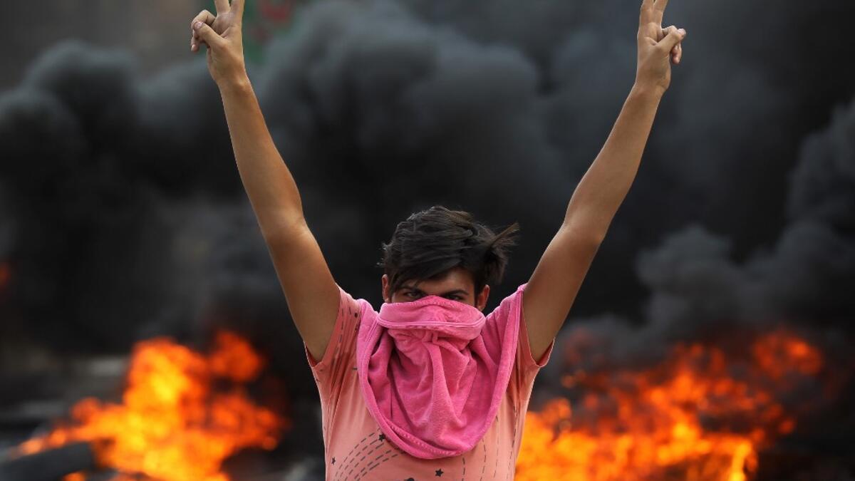 An Iraqi protester flashes the v-sign during a demonstration against state corruption, failing public services and unemployment in the Baladiyat district of the capital Baghdad on October 2, 2019. Iraq's president and the United Nations urged security forces to show restraint after two protesters were killed in clashes with police that other top officials blamed on "infiltrators." AHMAD AL-RUBAYE / AFP
