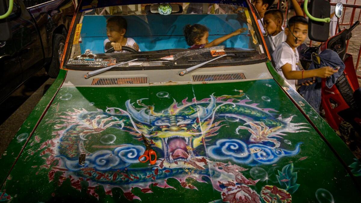 Children play in a car parked next to a Chinese shrine during the annual Vegetarian Festival in Phuket on October 2, 2019. Mladen ANTONOV / AFP