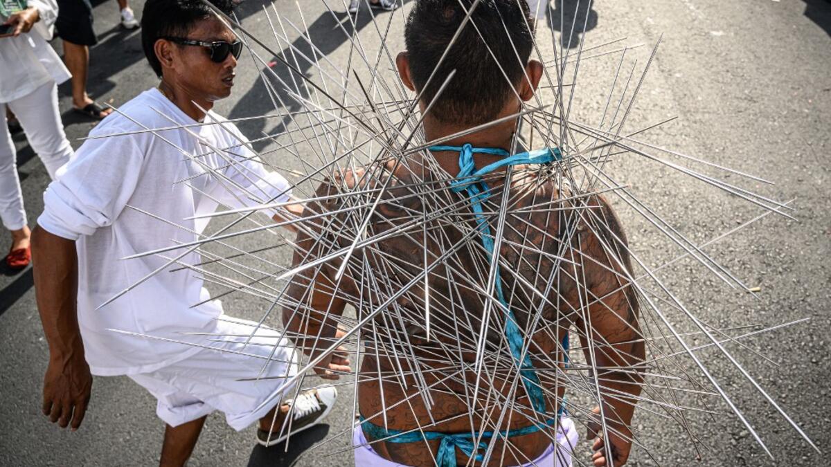 A devotee of a Chinese shrine with multiple needles pierced through his cheeks takes part in a procession during the annual Vegetarian Festival in Phuket on October 4, 2019.MLADEN ANTONOV / AFP