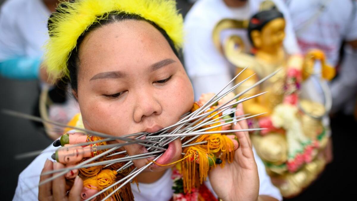 A devotee of a Chinese shrine with multiple skewers pierced through her cheeks takes part in a procession during the annual Vegetarian Festival in Phuket on October 5, 2019. Mladen ANTONOV / AFP