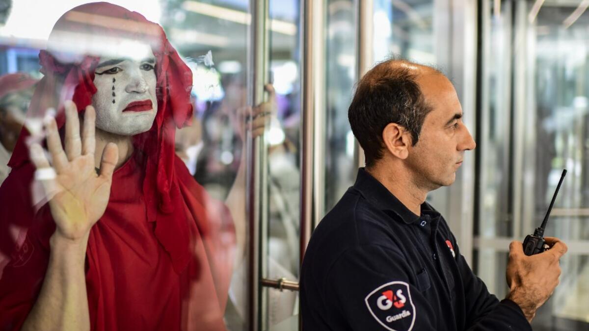 A protestor (L) takes part in a demonstration called by climate change activist group Extinction Rebellion, in front of the lobby of the building where the Bayer-Monsanto office is located in Buenos Aires on October 7, 2019. The year-old group Extinction Rebellion has energised a global movement demanding governments drastically cut the carbon emissions that scientists have shown to cause devastating climate change. RONALDO SCHEMIDT / AFP