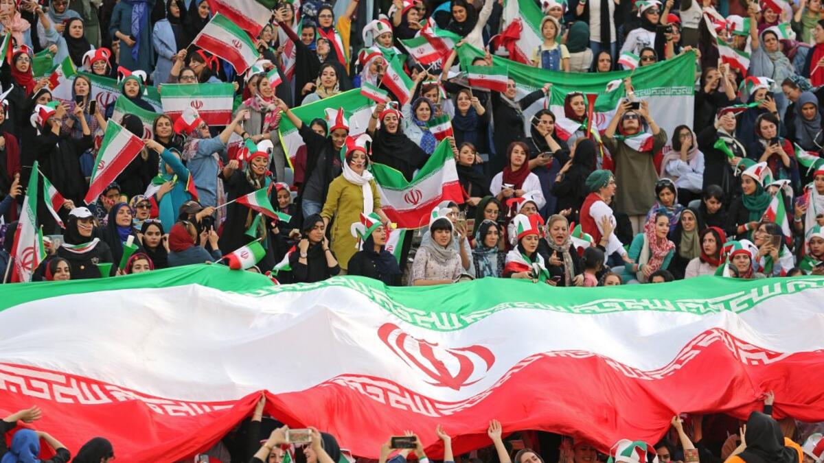 Iranian women cheer and wave their country's national flags as they attend the World Cup Qatar 2022 Group C qualification football match between Iran and Cambodia at the Azadi stadium in the capital Tehran on October 10, 2019. ATTA KENARE / AFP