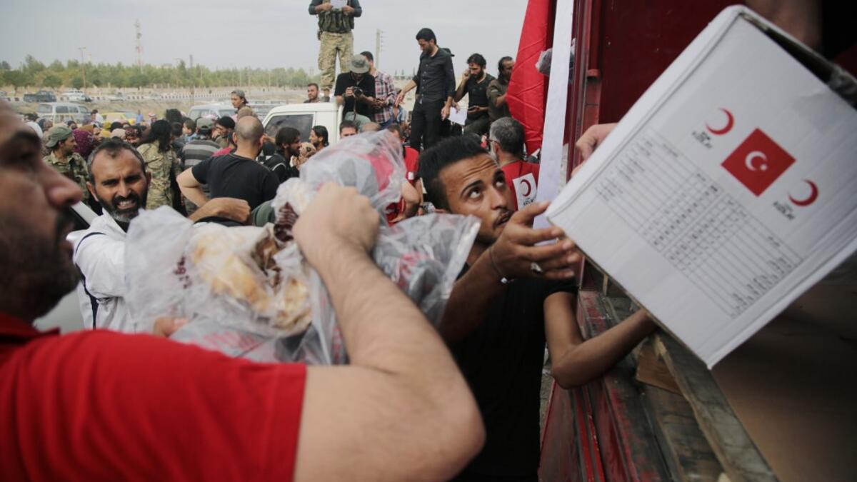 Displaced Syrians receive aid boxes provided by the Turkish Red Crescent on October 19, 2019, in the Syrian border town of of Tal Abyad which was seized by Turkey-backed forces last week. Bakr ALKASEM / AFP