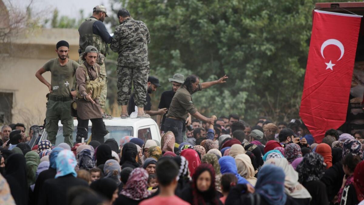 Members of Turkey-backed forces distribute aid provided by the Turkish Red Crescent on October 19, 2019, in the Syrian border town of of Tal Abyad which was seized last week. Bakr ALKASEM / AFP