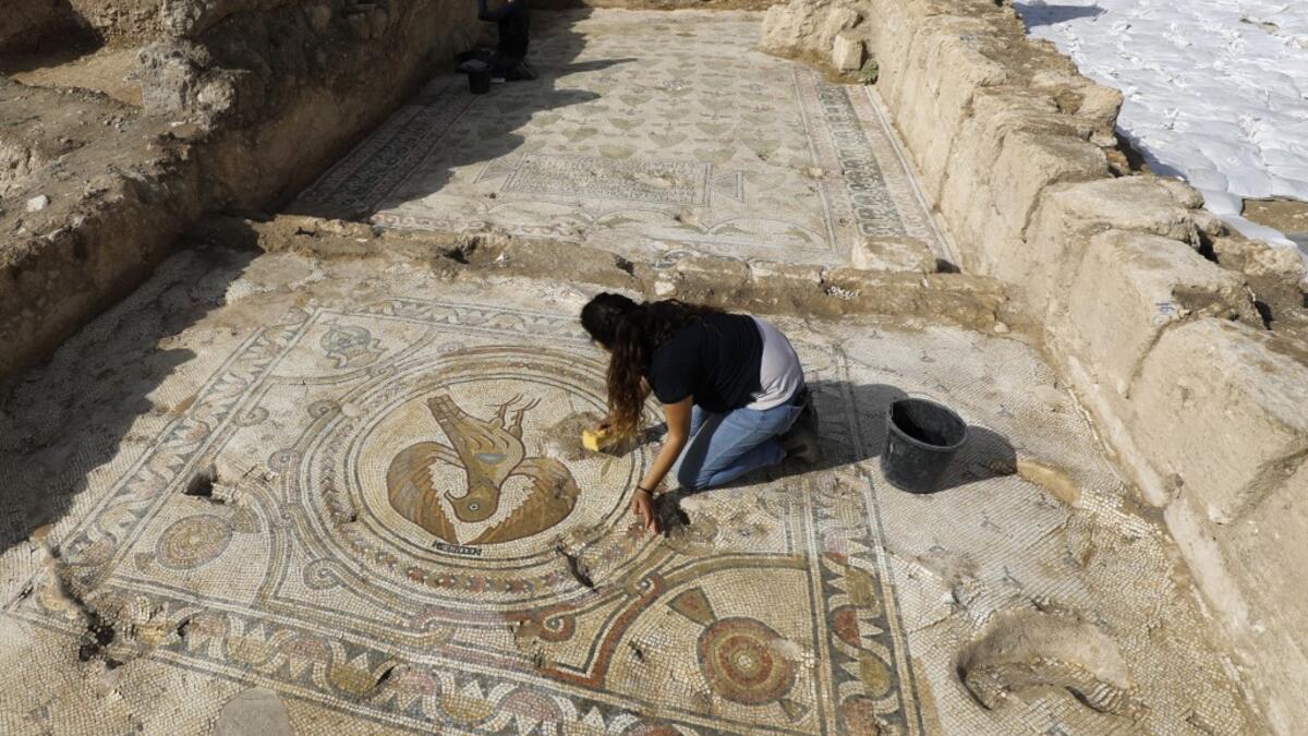 Timnah Goloubin (L), an archaeologist with the Israel Antiquities Authority, shows on October 23, 2019 a mosaic church floor of an Eagle symbol of the Byzantine Empire in the Israeli town of Beit Shemesh. A magnificent 1500-year-old church, decorated with spectacular mosaic floors and Greek inscriptions, was discovered during a three-year excavation near a residential area. MENAHEM KAHANA / afp