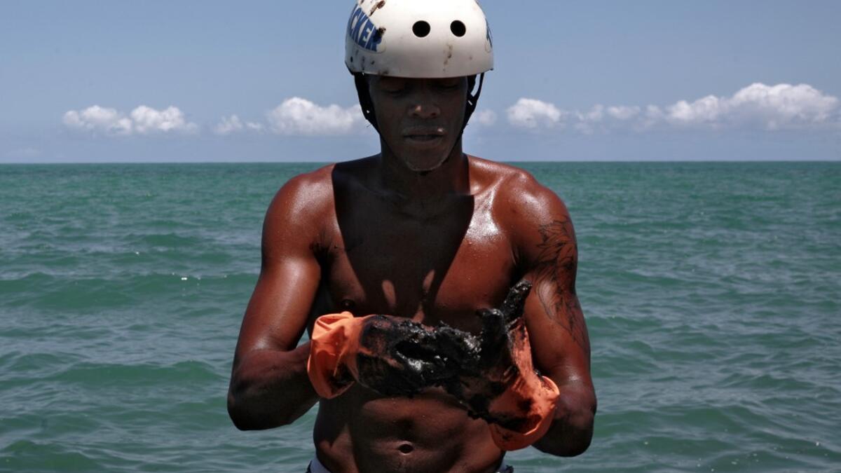 A volunteer removes crude spilled at Janga beach in Paulista, Pernambuco state, Brazil, on October 23, 2019. Large blobs of oil staining more than 130 beaches in northeastern Brazil began appearing in early September and have now turned up along a 2,000km stretch of the Atlantic coastline. Leo Malafaia / AFP
