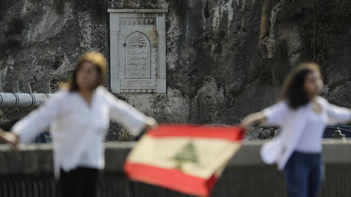 A picture taken on October 27, 2019, shows Lebanese protesters holding hands in the Nahr al-Kalb area, north of Beirut, to form a human chain along the coast from north to south as a symbol of unity, as part of ongoing anti-government demonstrations. The commemorative plaque carved in rock marks the full withdrawal of foreign troups in 1946, a couple of years after Lebanon's independence from the French mandate. JOSEPH EID / AFP