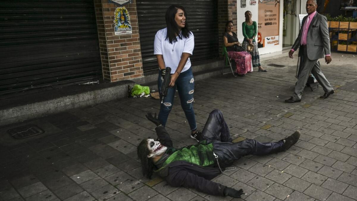 Venezuelan migrant Johnny Tales (R), who makes a living imitating the comicbook and film character "The Joker", poses for a photograph in a street of Medellin, on October 29, 2019. JOAQUIN SARMIENTO / AFP