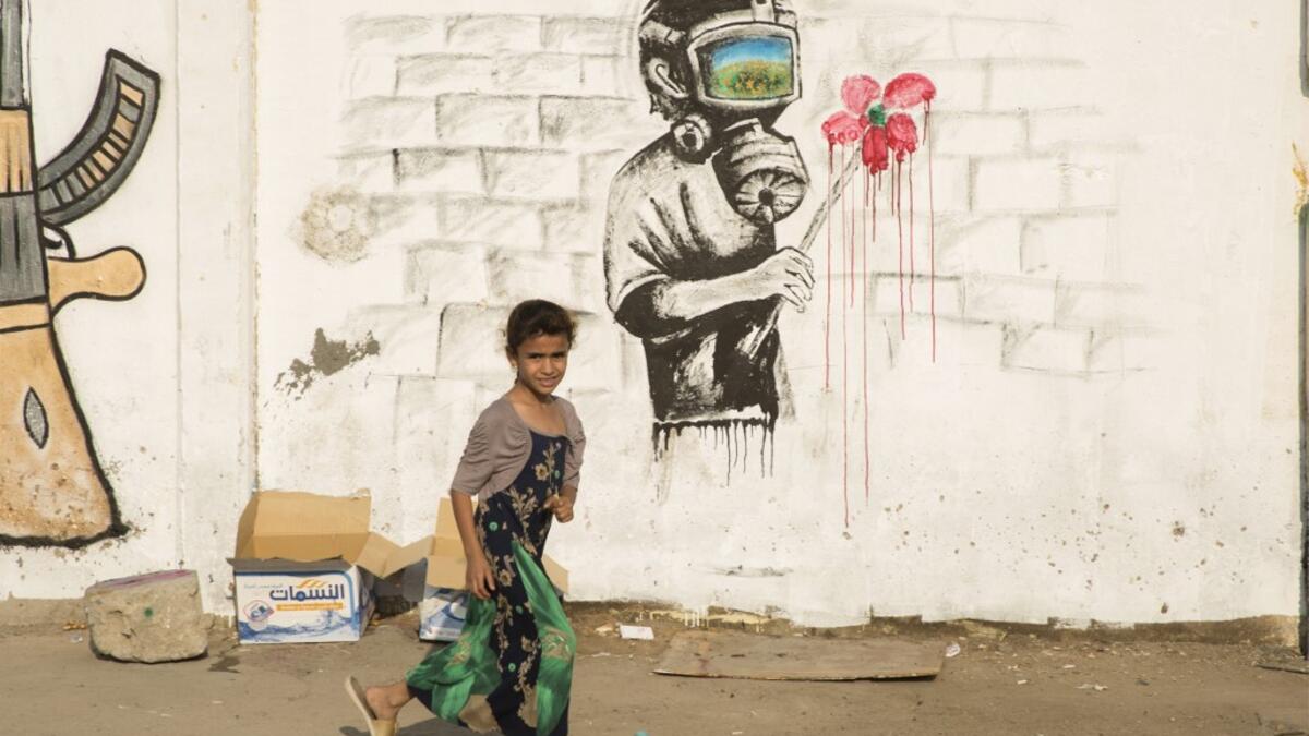 An Iraqi girl walks past a mural during ongoing anti-government demonstrations in the southern city of Basra on October 31, 2019. Iraqi security forces are using skull-piercing tear gas canisters against protesters, killing at least five in an "unprecedented" use of the weapon, Amnesty International said. Anti-government demonstrations have rocked the Iraqi capital and its south this month, leaving more than 250 people dead so far -- around half of them in the capital.   Hussein FALEH / AFP