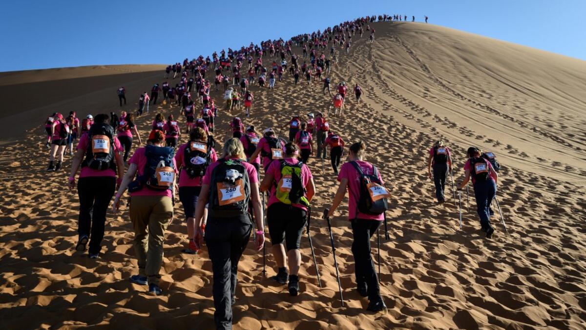 Women climb up a sand dune as they take part in the desert trek "Rose Trip Maroc", on November 4, 2019 in the erg Chebbi near Merzouga. The Rose Trip Maroc is a female-oriented trek where teams of three must travel through the southern Moroccan Sahara desert with a compass, a map and a topographical reporter. JEAN-PHILIPPE KSIAZEK / AFP