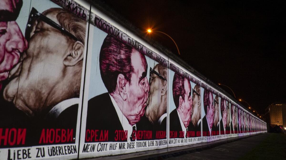 The mural painting "My God, Help Me to Survive This Deadly Love" by Russian painter Dmitri Vrubel, depicting the kiss between then Soviet leader Leonid Brezhnev (L) and East German leader Erich Honecker is projected on a stretch of the Berlin wall at the so-called East-side Gallery during the city-wide kick-off of the festival week to celebrate the 30th anniversary of the November 9,1989 fall of the Berlin Wall, in Berlin on November 4, 2019. Germany marks three decades since the fall of the Berlin Wall thi
