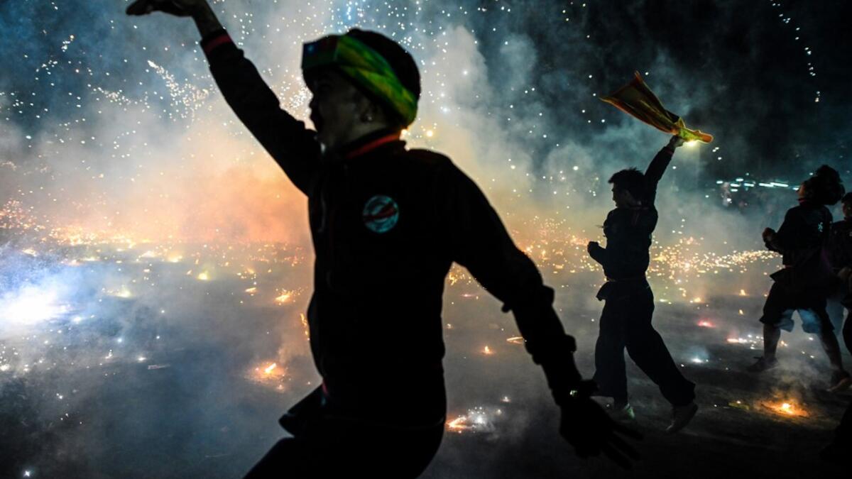 This picture taken on November 5, 2019 shows participants celebrating as fireworks explode after they released a hot-air balloon attached with fireworks during the Tazaungdaing Lighting Festival at Taunggyi in Myanmar's northeastern Shan State. Brightly coloured balloons with hundreds of homemade fireworks woven into their frames are sent soaring into the night sky, showering down cascades of sparks onto adoring crowds in the annual Taunggyi fire balloon festival. Ye Aung THU / AFP