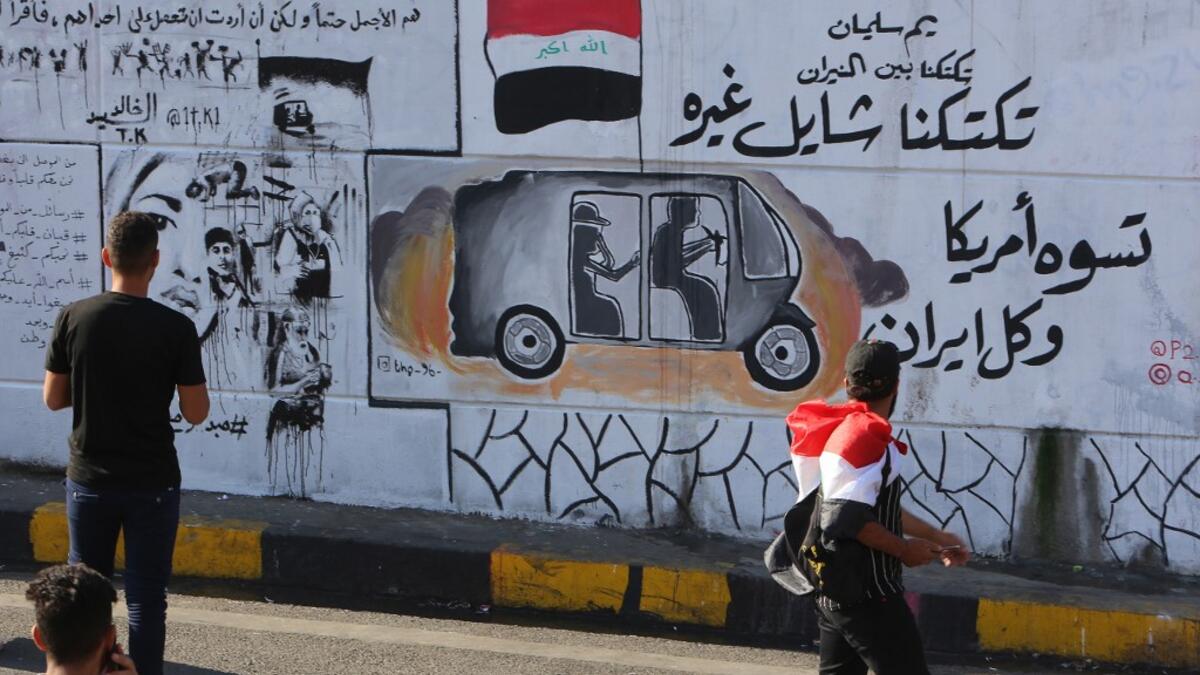 Iraqis walk past graffiti hailing Iraq's tuk-tuk drivers who have been helping protesters in Baghdad's Tahrir square, as the Iraqi capital braces for another day of protests on November 6, 2019. Arabic slogans on the wall read: "Our Tuk-tuk drivers are in the fire, they help others.. they are better than America and Iran together." The drivers of the motorised rickshaws, typically seen in poorer parts of the capital, have become the unofficial heros of the protest movement. SABAH ARAR / AFP