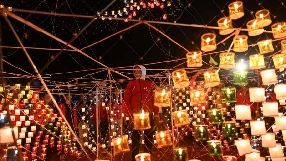 This picture taken on November 6, 2019 shows a reveller looking at lanterns attached to a hot-air balloon with fireworks during the Tazaungdaing Lighting Festival at Taunggyi in Myanmar's northeastern Shan State. Brightly coloured balloons with hundreds of homemade fireworks woven into their frames are sent soaring into the night sky, showering down cascades of sparks onto adoring crowds in the annual Taunggyi fire balloon festival. Ye Aung THU / AFP