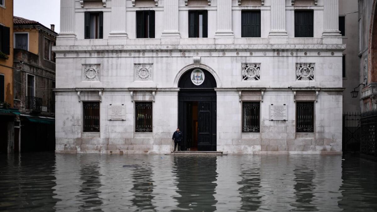 A man stands by the entrance of the Palazzo Patriarcale on the flooded Piazza dei Leoncini square after an exceptional overnight "Alta Acqua" high tide water level, early on November 13, 2019 in Venice. Powerful rainstorms hit Italy on November 12, with the worst affected areas in the south and Venice, where there was widespread flooding. Within a cyclone that threatens the country, exceptional high water were rising in Venice, with the sirocco winds blowing northwards from the Adriatic sea against the lago