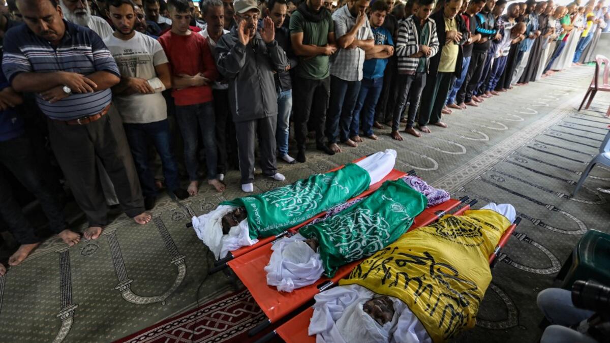 Palestinian mourners pray over the bodies of Rafat Ayad and his two sons Amir and Islam on during a funeral in Gaza City on November 13, 2019. Exchanges of fire triggered by Israel's targeted killing of a top militant in Gaza raged for a second day and showed little sign of easing, with 22 Palestinians killed. Fresh rocket barrages were fired at Israel, which responded with strikes on what it said were Islamic Jihad militant sites and rocket-launching squads in the Gaza Strip.  MAHMUD HAMS / AFP