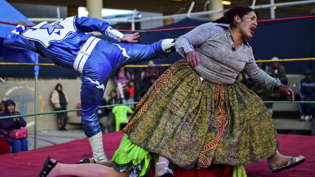 Bolivian wrestler Ana Luisa Yujra (R), aka "Jhenifer Two Faces", Lidia Flores (on the canvas), aka "Dina, The Queen of the Ring", both members of the Fighting Cholitas, and a wrestler fight at Sharks of the Ring wrestling club in El Alto, Bolivia, on November 24, 2019. After a fortnight hiatus due to anti-government protests and blockades, the Fighting Cholitas are back in the ring. The unrest was triggered by the disputed October 20 election, which Evo Morales claimed to have won and opposition groups said