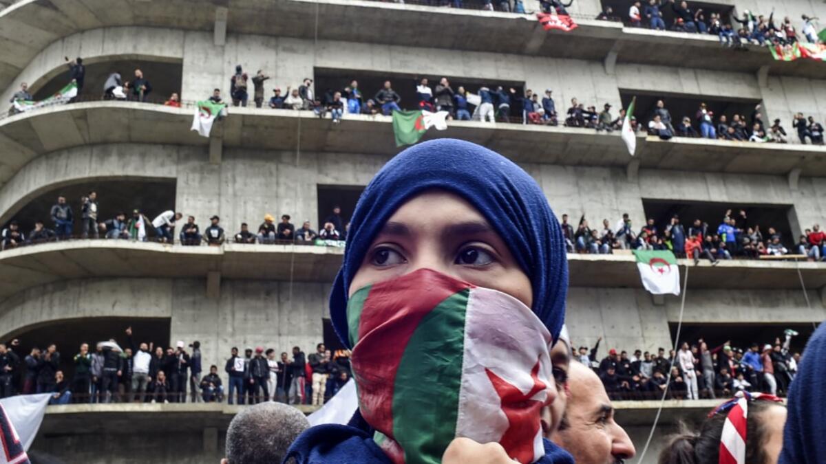 A woman covers her face with the national flag, as Algerian protesters demonstrate in the capital Algiers against ailing president's bid for a fifth term on March 8, 2019. Tens of thousands protested across Algeria today in the biggest rallies yet against ailing President Abdelaziz Bouteflika's bid for a fifth term, despite the defiant leader's warning of the risk of "chaos". RYAD KRAMDI / AFP