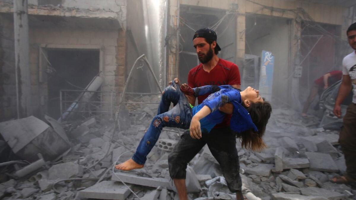 A man evacuates a young bombing casualty after a reported air strike by regime forces and their allies in the jihadist-held Syrian town of Maaret Al-Noman in the southern Idlib province, on May 26, 2019. Regime air strikes killed 12 civilians including four at a market today in a jihadist bastion in northwest Syria, a war monitor said. Abdulaziz KETAZ / AFP