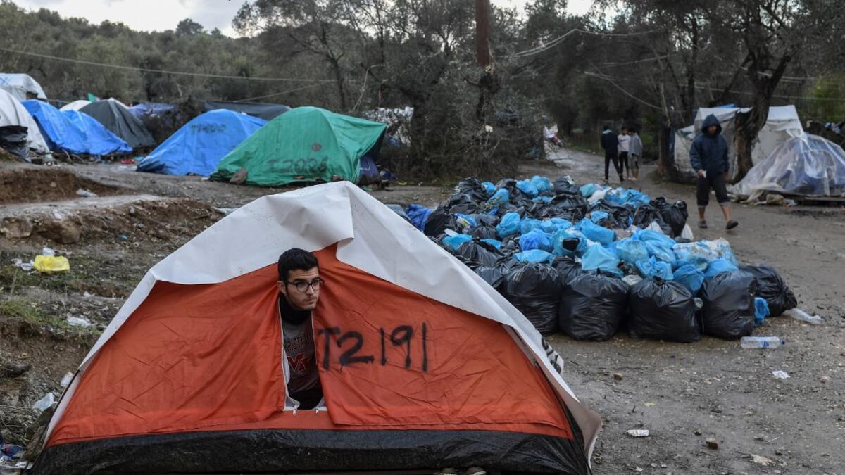 A man peers outside his tent at the makeshift camp next to the overcrowded refugee camp of Moria near the capital Mytilene in the island of Lesbos on November 29, 2019. ARIS MESSINIS / AFP