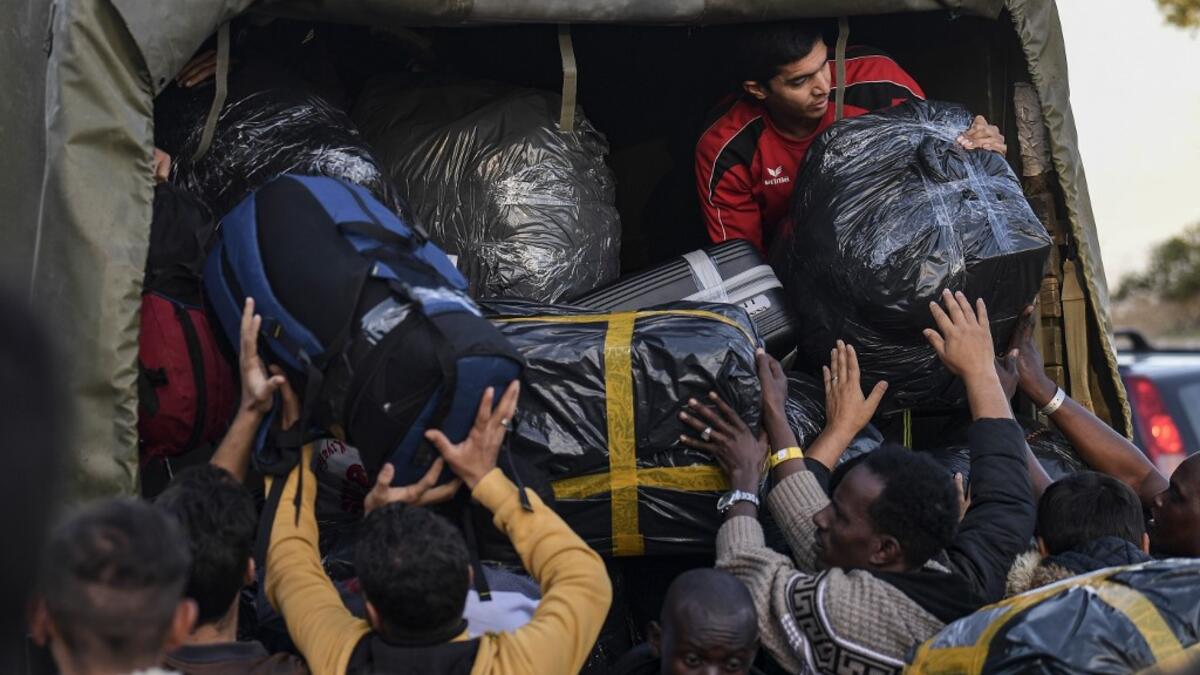 Refugees and migrants load their belongings onto a truck as they depart from the Greek island camp of Moria on Lesbos to Athens on November 29, 2019. Conditions remain difficult in the overcrowded camp counting over 18,000 people with winter fast approaching. Last week the government announced it will shut down the three largest of its overcrowded migrant camps on islands facing Turkey, and replace them with new closed facilities with much larger capacity. ARIS MESSINIS / AFP