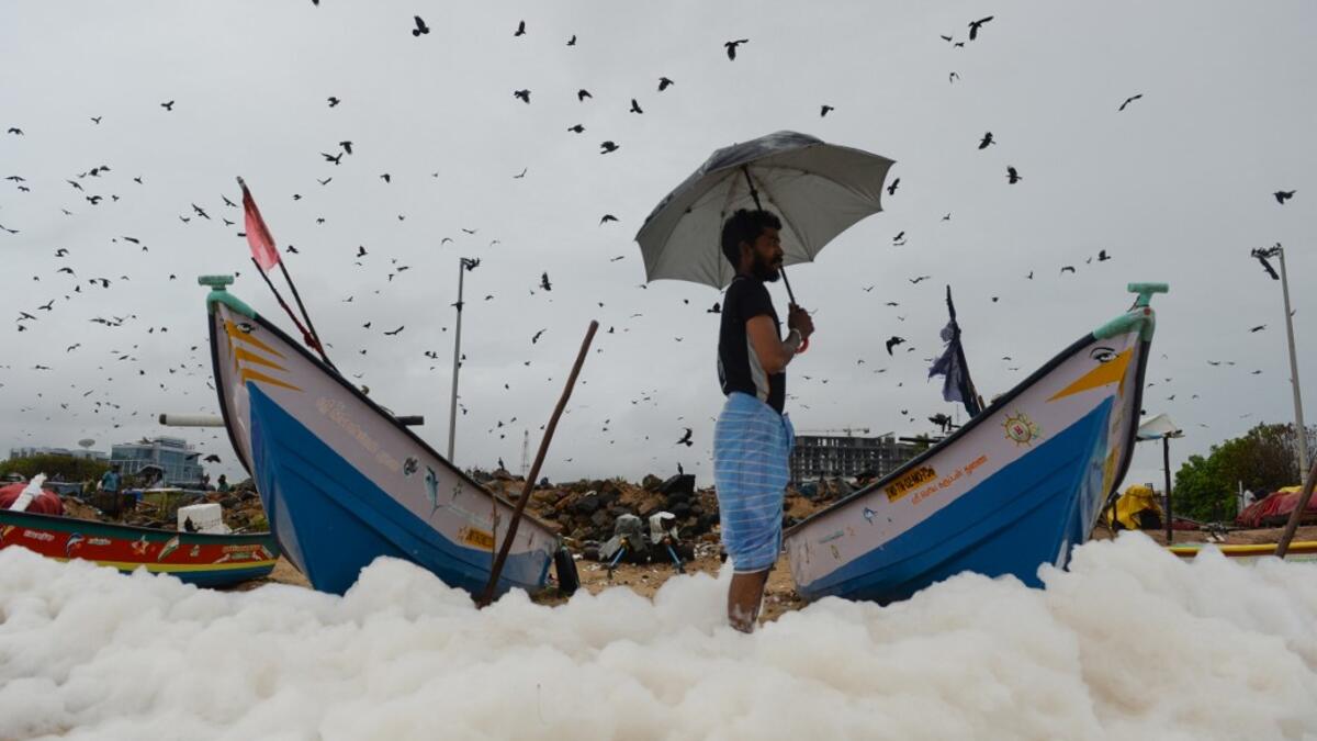 A man looks on as foamy discharge, caused by pollutants, mix with surf at Marina beach in Chennai on December 1, 2019. Arun SANKAR / AFP
