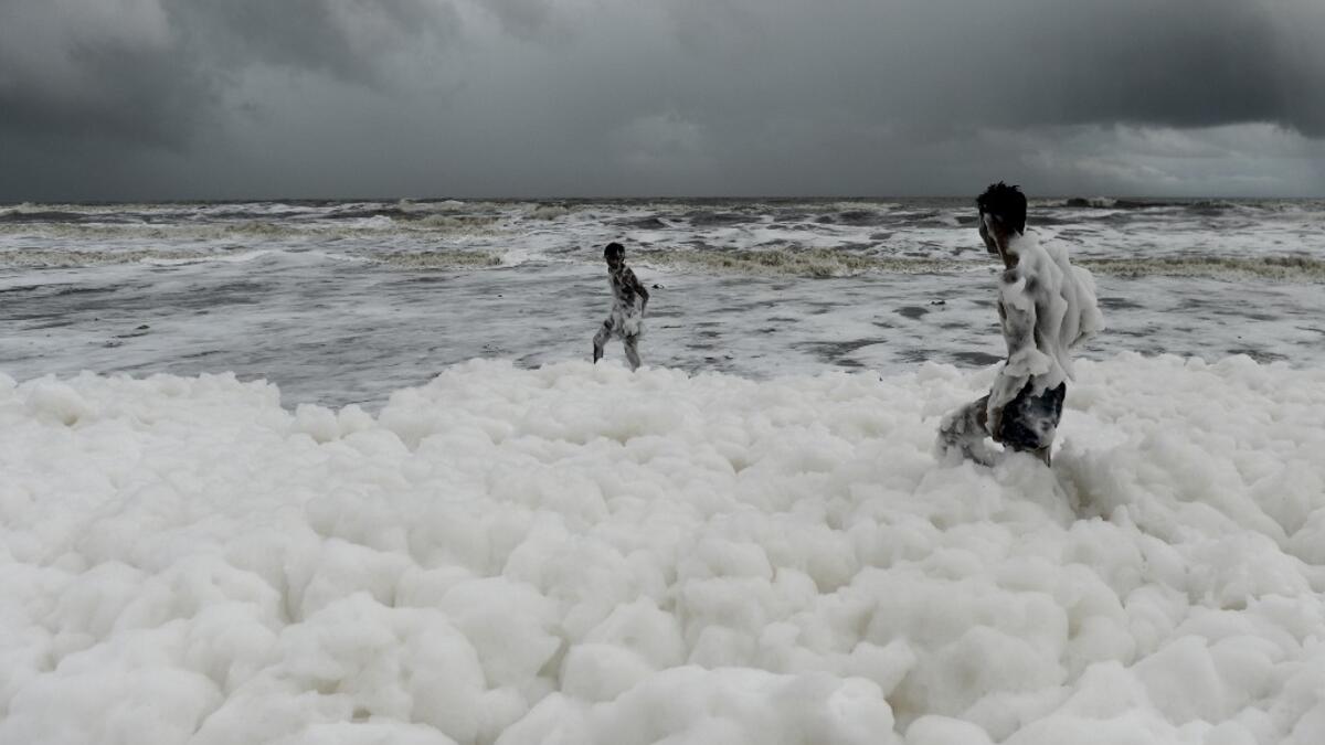 Residents play over foamy discharge, caused by pollutants, as it mixes with the surf at Marina beach in Chennai on December 1, 2019. Arun SANKAR / AFP