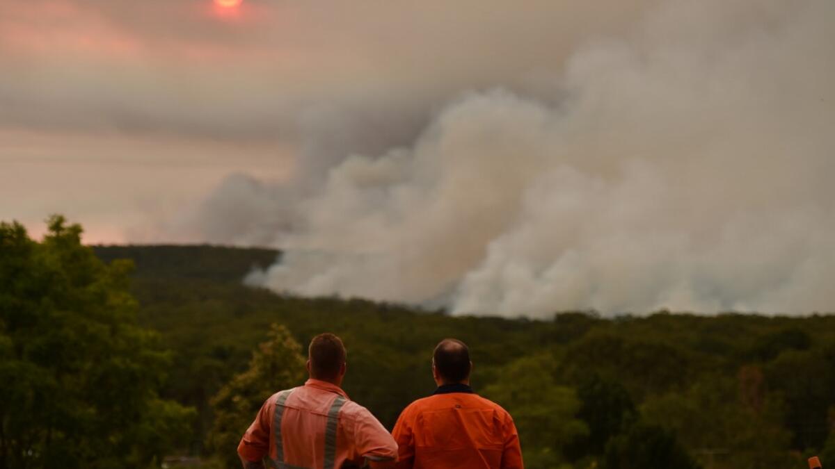 Residents watch a large bushfire as seen from Bargo, 150km southwest of Sydney, on December 19, 2019. A state of emergency was declared in Australia's most populated region on December 19 as an unprecedented heatwave fanned out-of-control bushfires, destroying homes and smothering huge areas with a toxic smoke. Peter PARKS / AFP