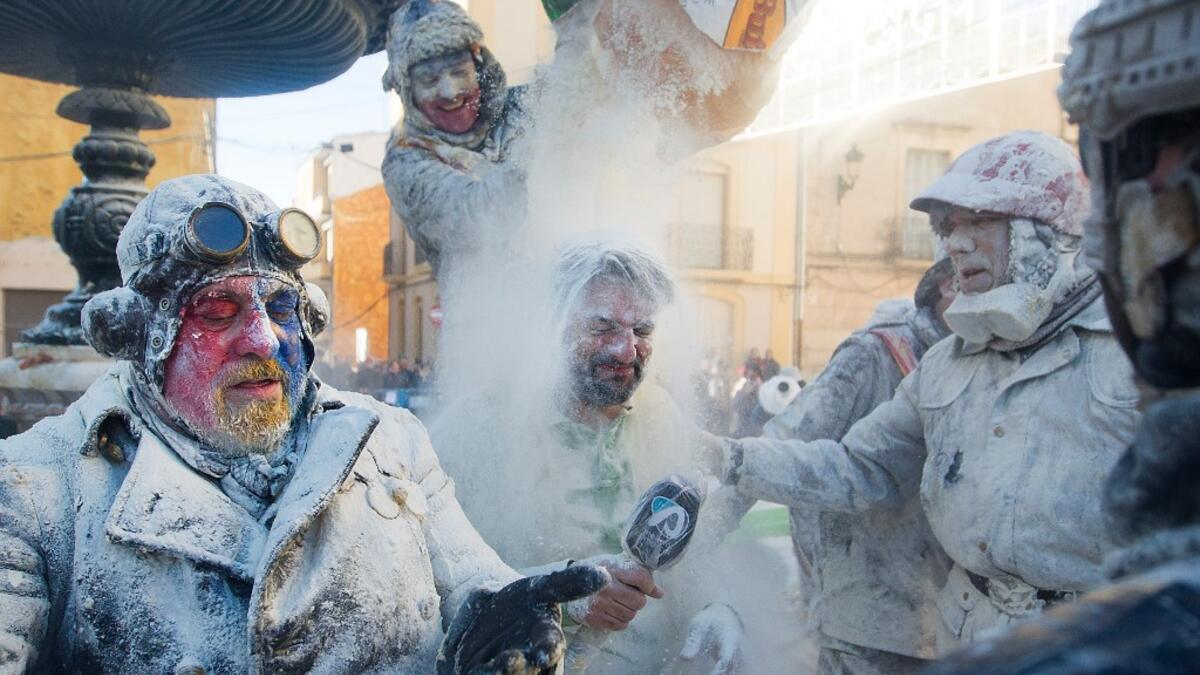 A reveller dressed in mock military garb empties out a sack of flour over a journalist during the "Els Enfarinats" battle in the southeastern Spanish town of Ibi on December 28, 2019. During this 200-year-old traditional festival participants known as Els Enfarinats (those covered in flour) dress in military clothes and stage a mock coup d'etat as they battle using flour, eggs and firecrackers outside the city town hall as part of the celebrations of the Day of the Innocents, a traditional day in Spain for