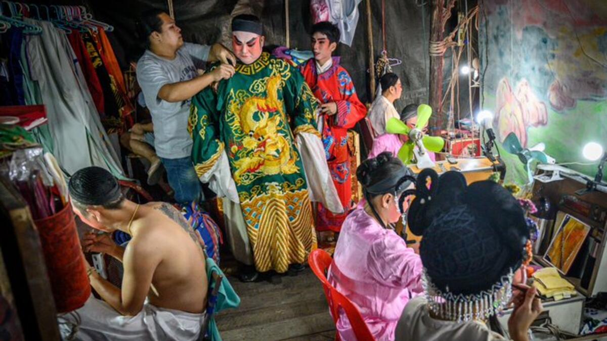 This photograph taken on December 28, 2019 shows actors preparing for a Chinese opera performance by Thailand's Sai Bo Hong troupe on a makeshift stage at a street festival in Bangkok. An ancient world of swords, warriors and folklore roars to life on the darkened street, offering a momentary escape from the modern-day bustle of Bangkok's unstoppable development. For centuries, troupes like the Sai Bo Hong Chinese opera have performed throughout Thailand, where 14 percent of the population are ethnic Chines