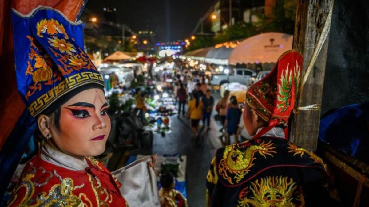 This photograph taken on December 28, 2019 shows actors looking behind the curtains before a Chinese opera performance by Thailand's Sai Bo Hong troupe on a makeshift stage at a street festival in Bangkok. An ancient world of swords, warriors and folklore roars to life on the darkened street, offering a momentary escape from the modern-day bustle of Bangkok's unstoppable development. For centuries, troupes like the Sai Bo Hong Chinese opera have performed throughout Thailand, where 14 percent of the populat