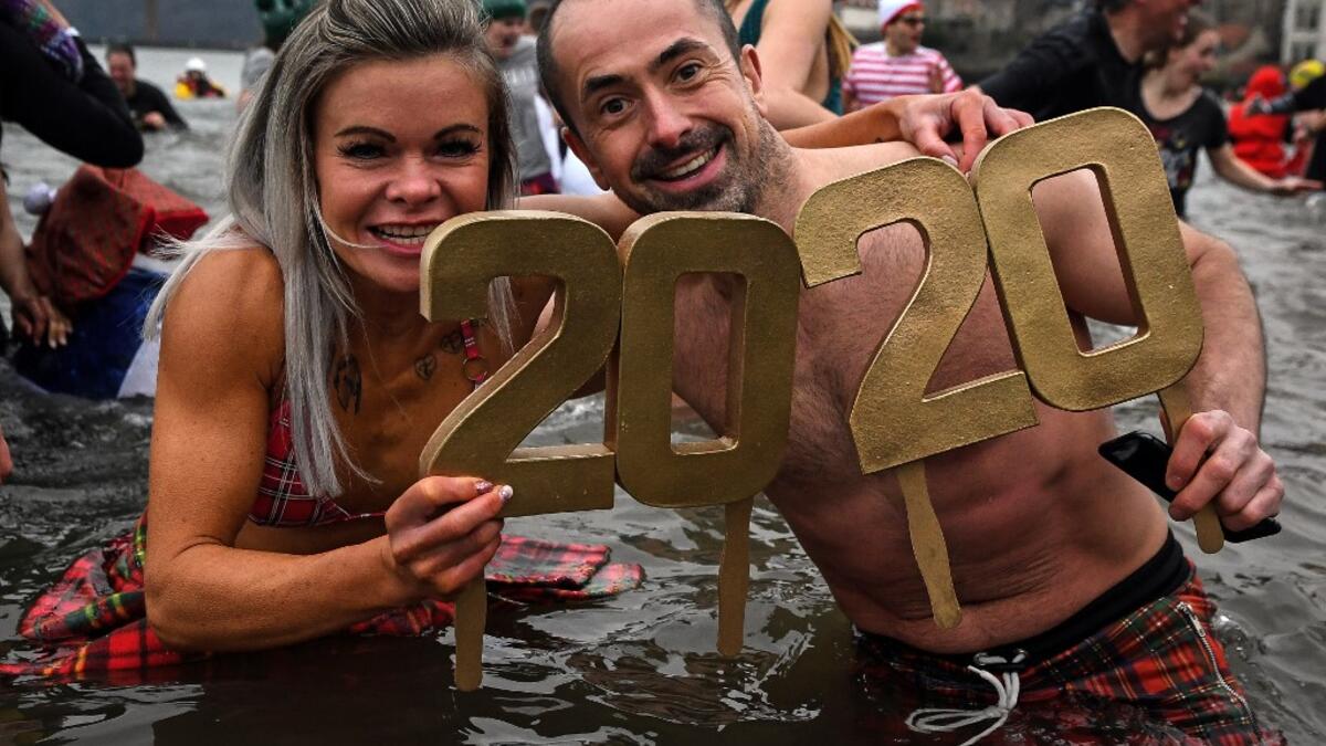 Participants pose in the water as they take part in the annual New Year's Day "Loony Dook" swim, in the Firth of Forth, in South Queensferry, near Edinburgh, on January 1, 2020. Every year people brave the River Forth, near the Forth Bridge, on New Year's Day to see in the New Year and raise money for charity. ANDY BUCHANAN / AFP