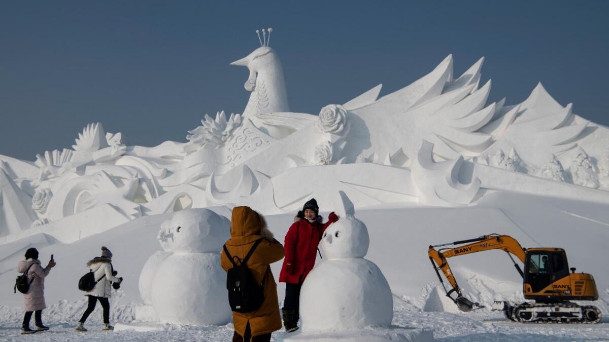 Tourist pose in front of an ice sculpture ahead of the opening of the Harbin International Ice and Snow Festival in Harbin, in China's northeast Heilongjiang province on January 4, 2020. NOEL CELIS / AFP