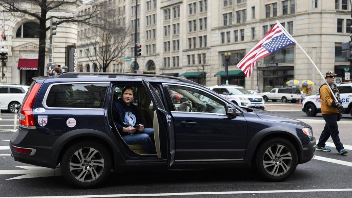 A man watches from a car as anti-war activist demonstrate outside the Trump International Hotel in Washington, DC, on January 4, 2020.ANDREW CABALLERO-REYNOLDS / AFP
