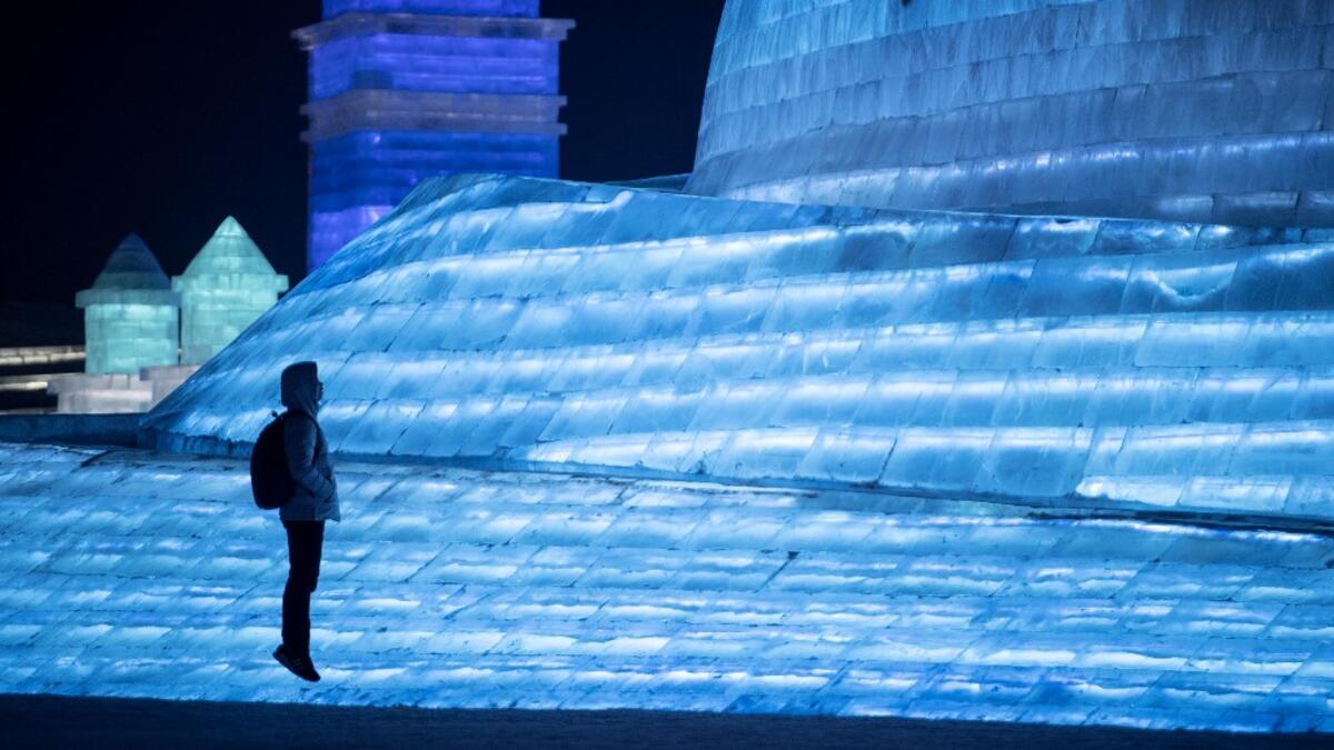 A tourist jumps in front of an ice sculpture during the Harbin International Ice and Snow Festival in Harbin, in China's northeast Heilongjiang province on January 5, 2020. Noel CELIS / AFP