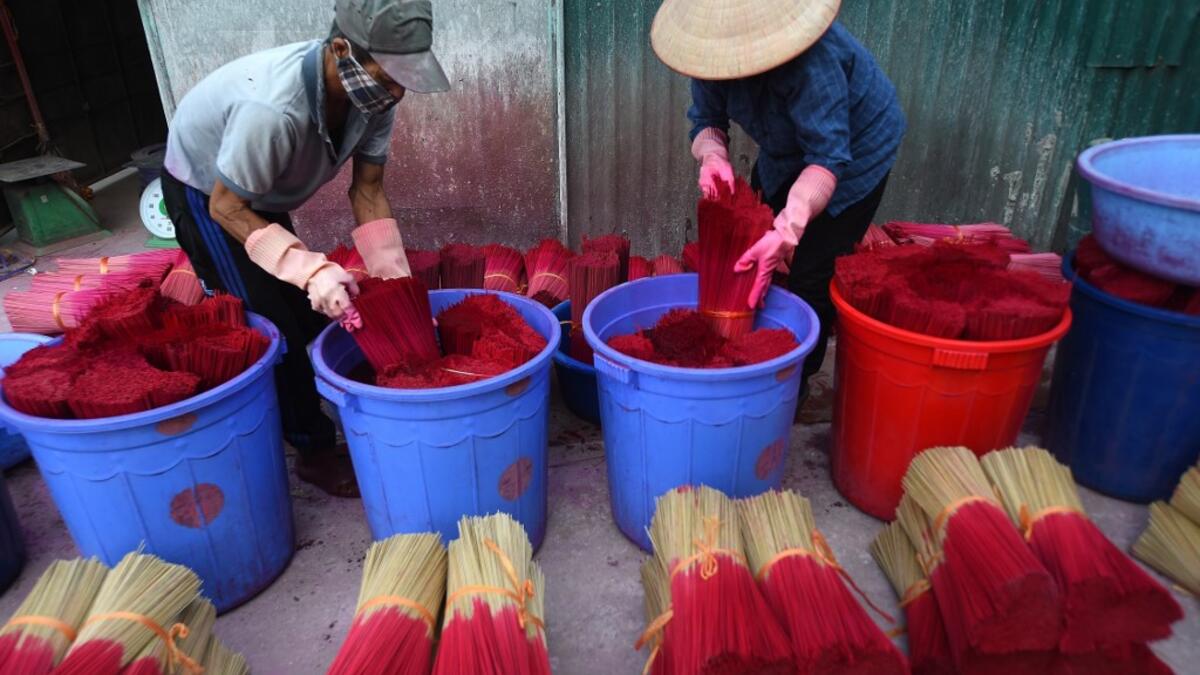 Vietnamese workers dye incense sticks in Quang Phu Cau village on the outskirts of Hanoi on January 9, 2020 ahead of the upcoming Lunar New Year celebrations, referred to in Vietnam as Tet. Nhac NGUYEN / AFP