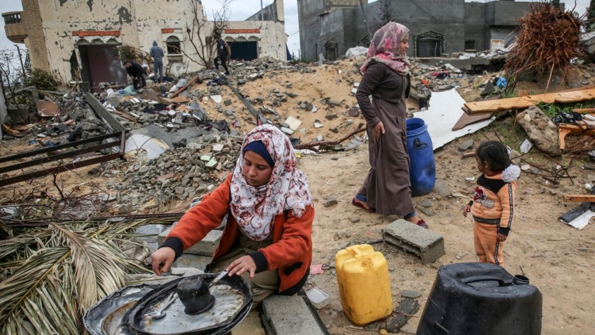 A Palestinian woman carries washes the dishes outside her shack in Khan Yunis in the southern Gaza Strip on January 10, 2020. A family of 17, whose house was destroyed by an Israeli air strike last November, now live in a shack in cold weather and heavy rain. SAID KHATIB / AFP