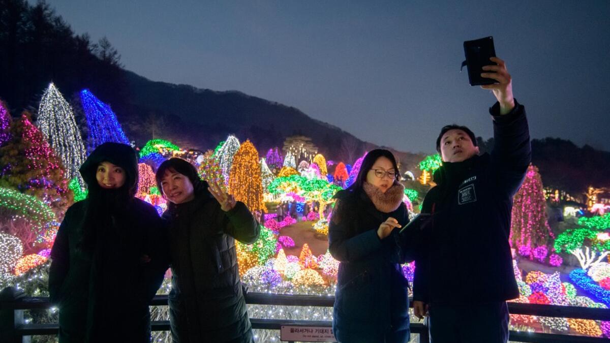 In a photo taken on January 11, 2020 visitors take a selfie as they look at an annual light display at the 'Garden on Morning Calm', near Gapyeong, east of Seoul. Ed JONES / AFP